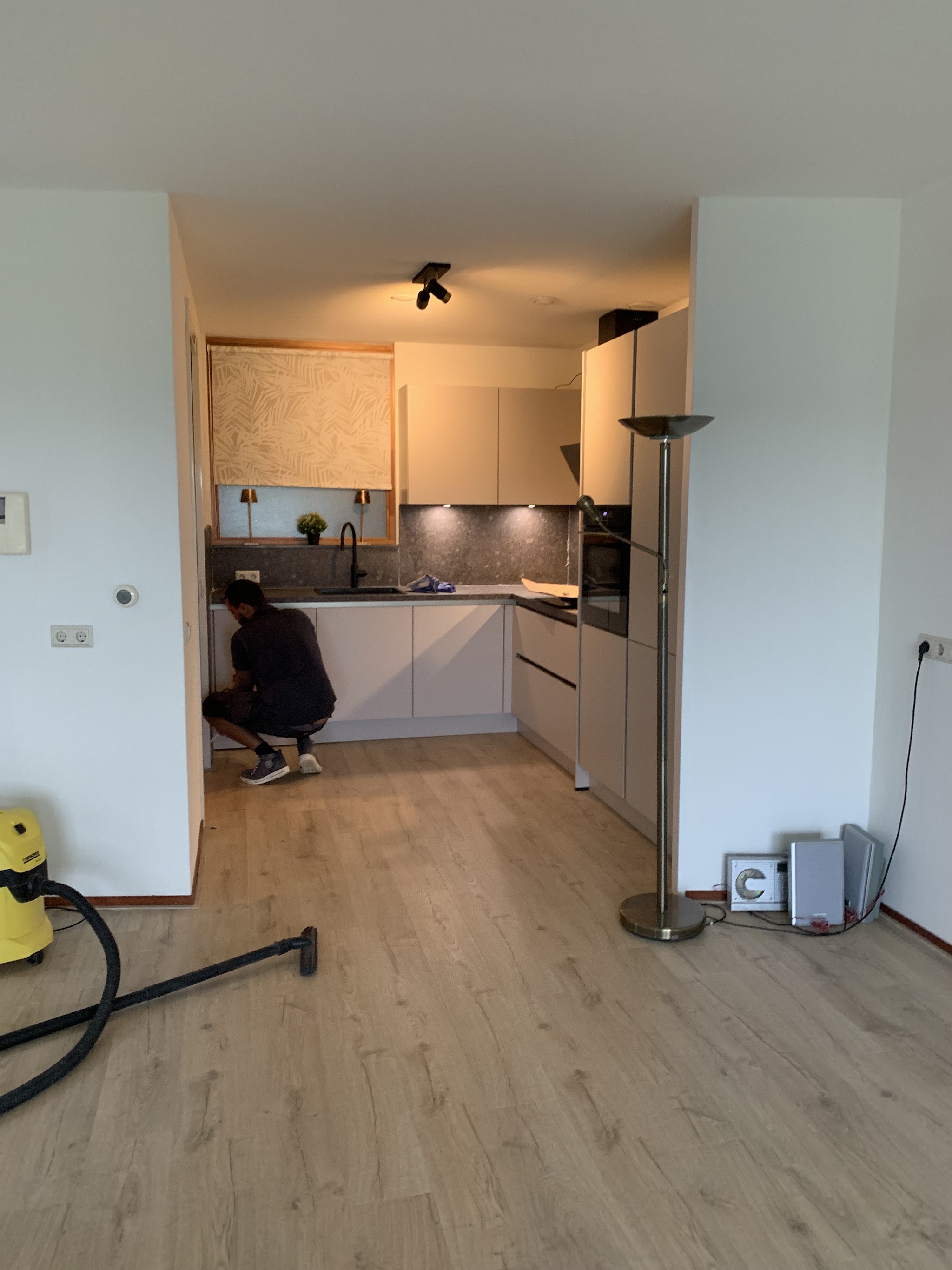 Lichte keuken tijdens de afronding, een monteur aan het werk bij de onderkasten